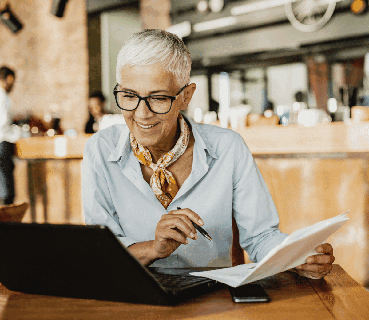Personne senior professionnelle examinant des documents et écran, symbolisant le travail des seniors